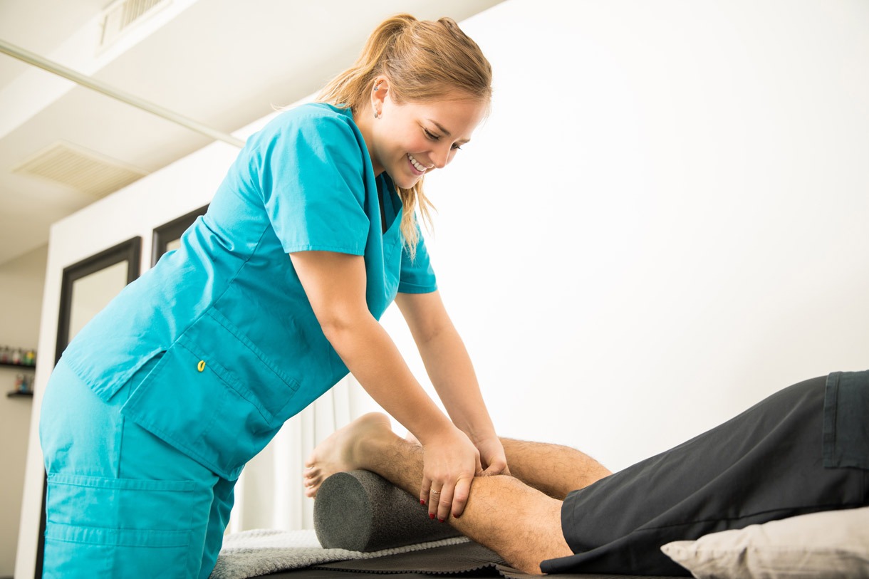 smiling physiotherapy specialist giving massage patient calf pain relief hospital