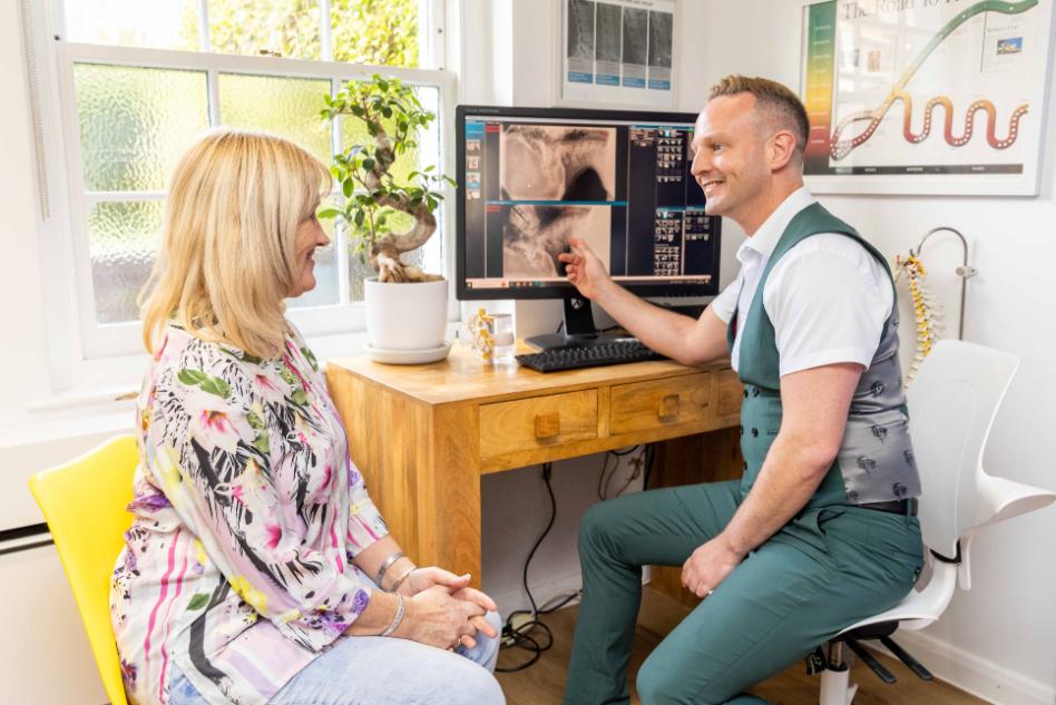 Chiropractor assessing patient’s lower back during spinal stenosis treatment consultation using modern chiropractic techniques.