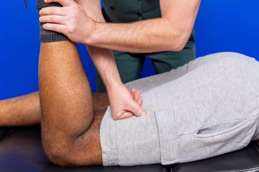 Chiropractor performing a hamstring muscle strength test on a patient’s leg during a physical assessment at a chiropractic clinic in Surbiton.