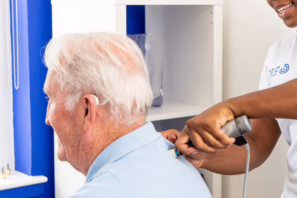 Chiropractor using an instrument-assisted thoracic adjustment device on an elderly patient’s upper back during treatment in a chiropractic clinic.