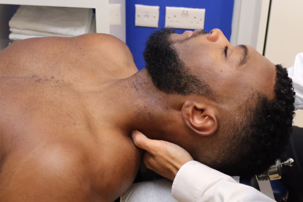 Man receiving neck adhesion release treatment from a chiropractor in a Surbiton clinic, with gentle manual therapy applied to the side of the neck.