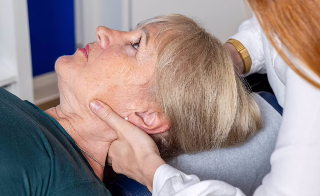 Woman receiving a gentle neck adjustment from a chiropractor at a clinic in Surbiton, with hands supporting her head and neck during treatment.