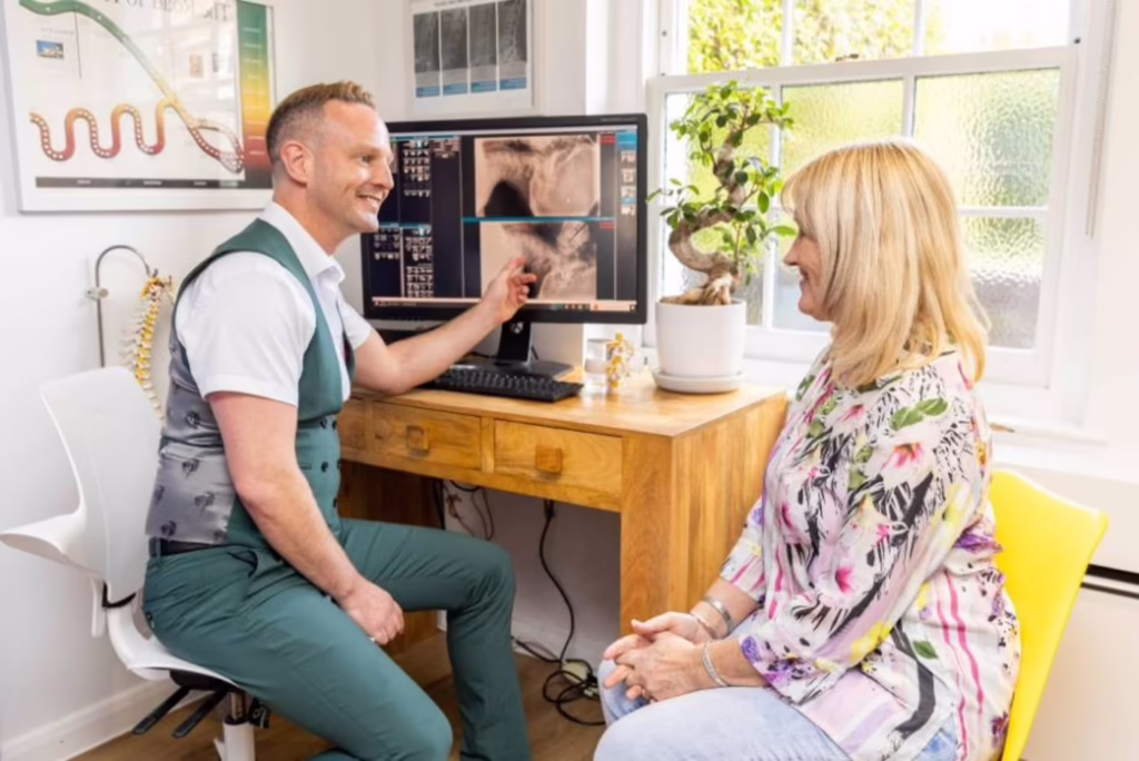 A chiropractor reviewing spinal X-rays with a patient during a consultation at a clinic in Surbiton.