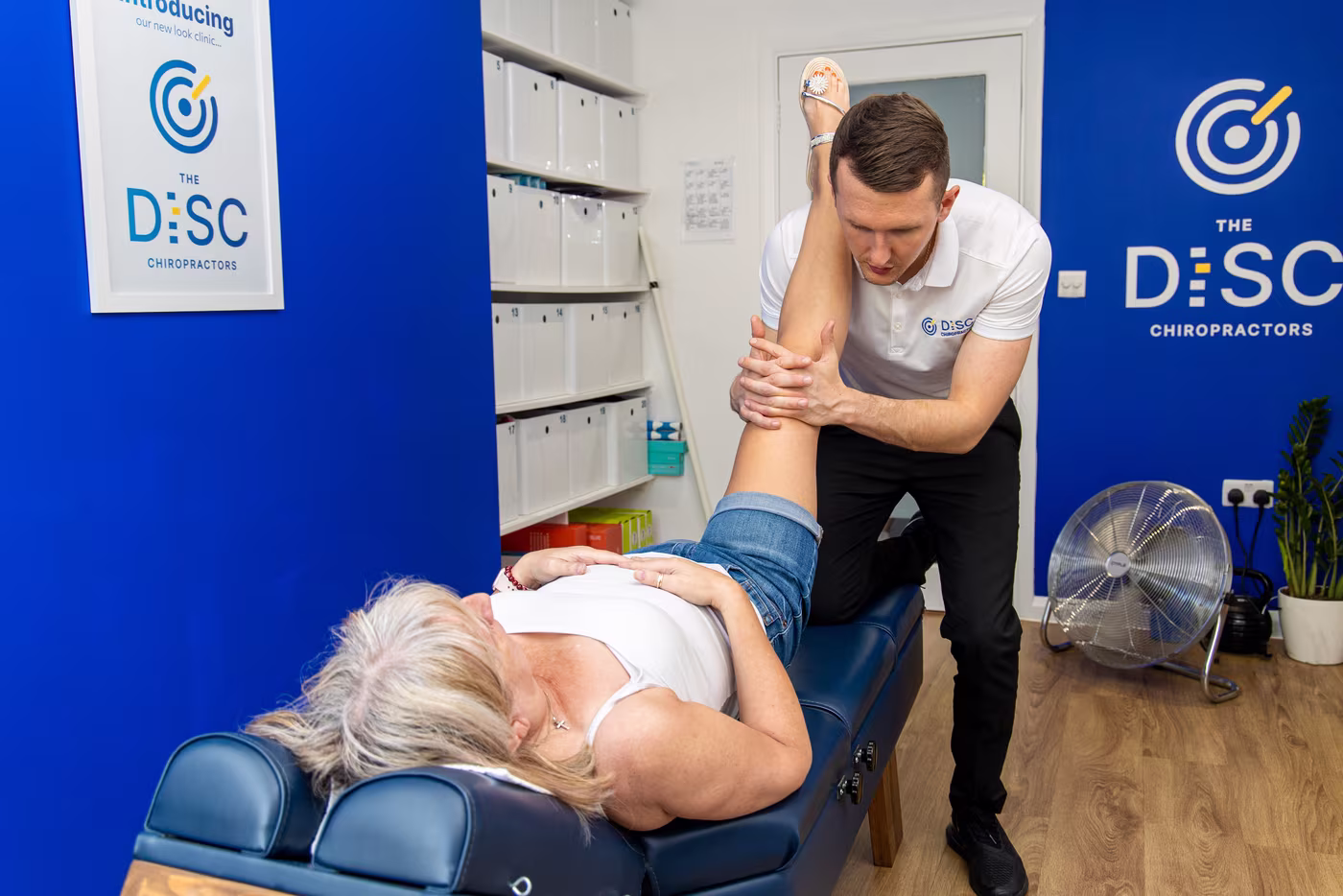 Chiropractor raising a patient's straightened leg to test for nerve irritation.